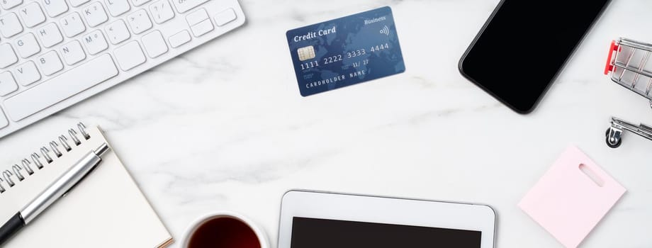 Top view of online shopping concept with credit card and electronics isolated on office marble white table background.