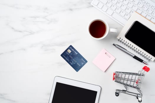 Top view of online shopping concept with credit card and electronics isolated on office marble white table background.