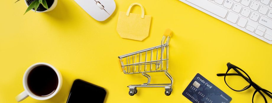 Top view of online shopping concept with credit card, smart phone and computer isolated on office yellow table background.