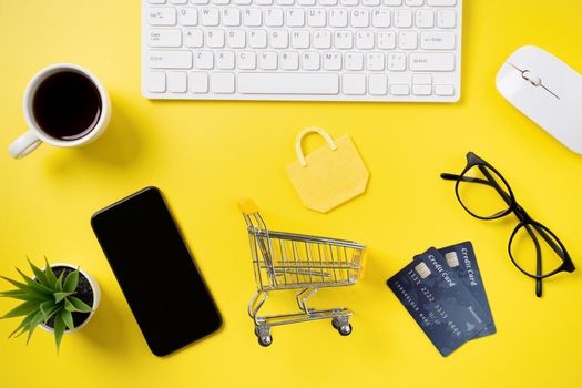 Top view of online shopping concept with credit card, smart phone and computer isolated on office yellow table background.