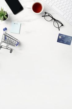 Top view of online shopping concept with credit card, smart phone and computer isolated on office marble white table background.