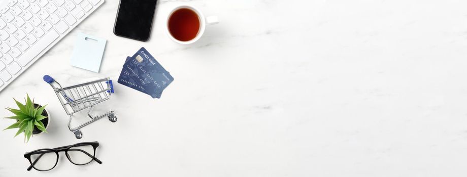 Top view of online shopping concept with credit card, smart phone and computer isolated on office marble white table background.