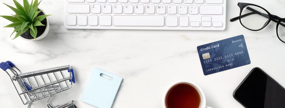 Top view of online shopping concept with credit card, smart phone and computer isolated on office marble white table background.