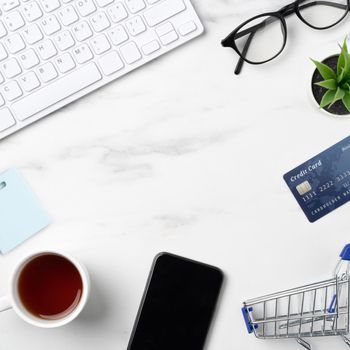 Top view of online shopping concept with credit card, smart phone and computer isolated on office marble white table background.