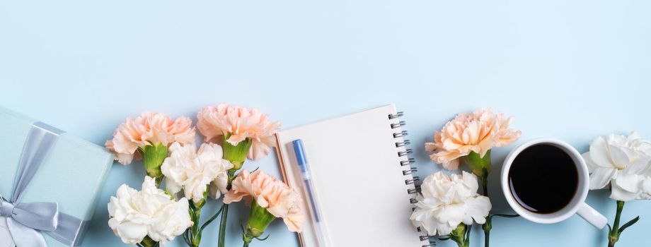 Design concpet of Mother's Day greeting with carnation flower, holiday gift idea and notebook diary on mother's desk background.