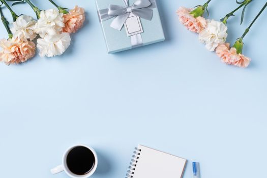 Design concpet of Mother's Day greeting with carnation flower, holiday gift idea and notebook diary on mother's desk background.