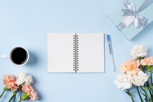Design concpet of Mother's Day greeting with carnation flower, holiday gift idea and notebook diary on mother's desk background.