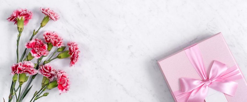 Concept of Mother's day holiday greeting gift design with carnation bouquet on white marble background