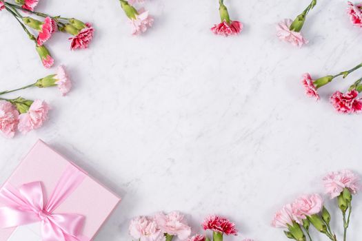 Concept of Mother's day holiday greeting gift design with carnation bouquet on white marble background
