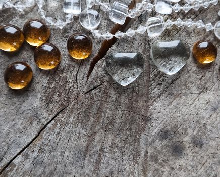 Two transparent hearts and beads on the rough surface of an old stump. Perfect Valentine's Day greeting card background.