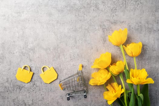 Concept of Mother's day holiday gift shopping greeting design with yellow tulip flower bouquet on gray background