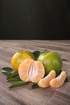 Fresh green tangerine mandarin orange with fresh leaves on dark wooden table background harvest concept.