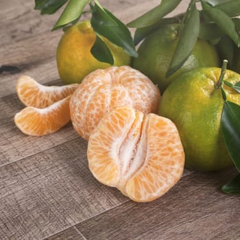 Fresh green tangerine mandarin orange with fresh leaves on dark wooden table background harvest concept.