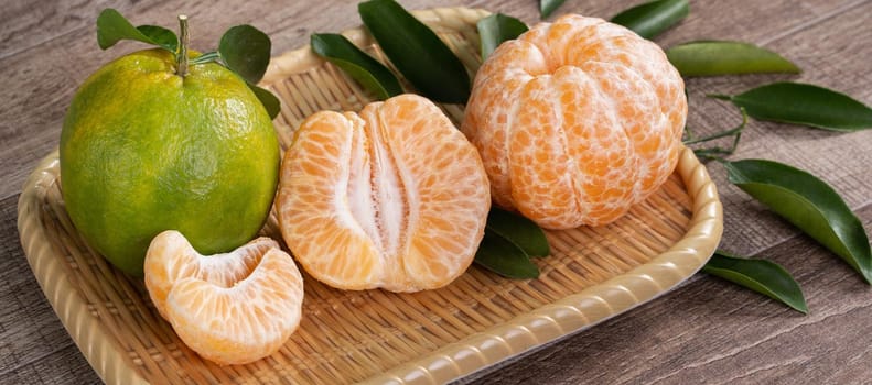 Fresh green tangerine mandarin orange with fresh leaves on dark wooden table background harvest concept.