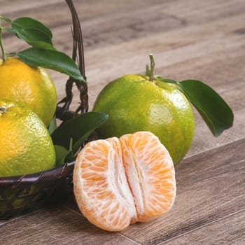 Fresh green tangerine mandarin orange with fresh leaves on dark wooden table background harvest concept.