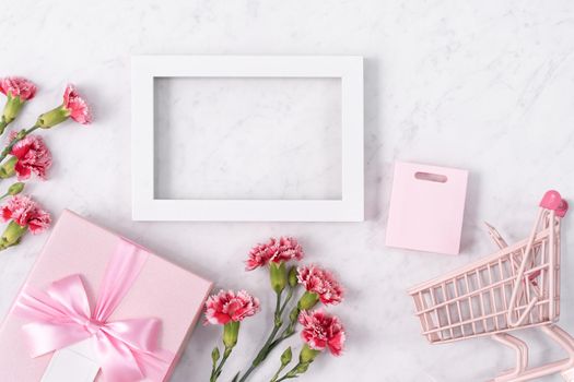Concept of Mother's day holiday greeting design with carnation bouquet and gift on white marble background