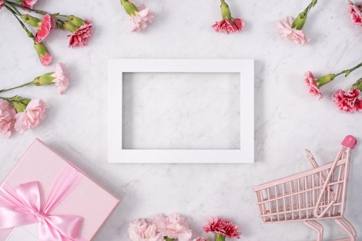 Concept of Mother's day holiday greeting design with carnation bouquet and gift on white marble background