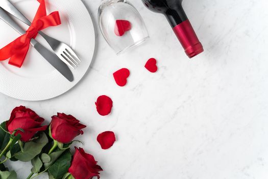 White plate with red rose flower on marble white table background for Valentine's Day dating holiday meal concept.