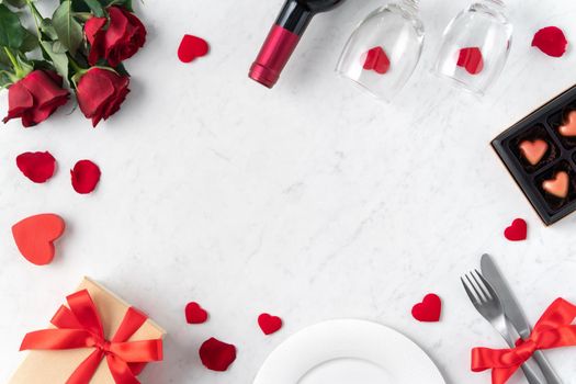 White plate with red rose flower on marble white table background for Valentine's Day dating holiday meal concept.