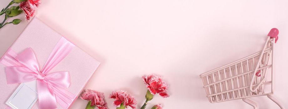 Concept of Mother's day holiday greeting design with carnation bouquet and gift on pink background