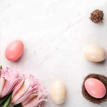 Colorful Easter eggs in the nest with pink lily flower on bright marble white table background.