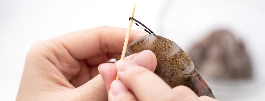 Woman deveins shrimp and pull out intestinal tract line when cooking shrimp.