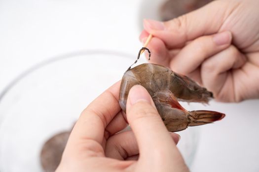 Woman deveins shrimp and pull out intestinal tract line when cooking shrimp.