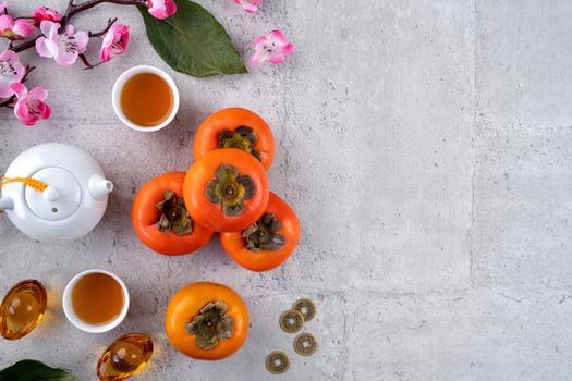 Fresh persimmons on gray table background for Chinese new year fruit design, words on the golden coin means the Dynasty name it made.