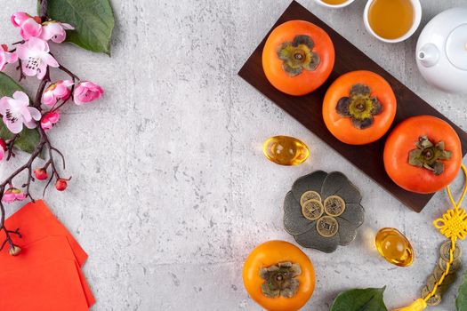 Fresh persimmons on gray table background for Chinese new year fruit design, words on the golden coin means the Dynasty name it made.
