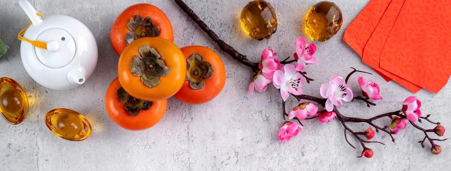 Fresh persimmons on gray table background for Chinese new year fruit design, words on the golden coin means the Dynasty name it made.