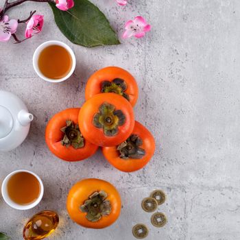 Fresh persimmons on gray table background for Chinese new year fruit design, words on the golden coin means the Dynasty name it made.