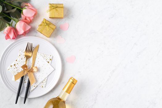 White plate with gift and pink rose flower on marble white table background for Valentine's Day special holiday dating meal concept.