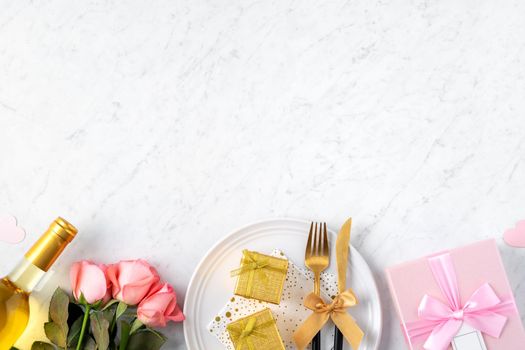White plate with gift and pink rose flower on marble white table background for Valentine's Day special holiday dating meal concept.