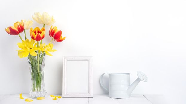 Tulip flower in glass vase with picture frame on white wall, Mother's Day decor concept.