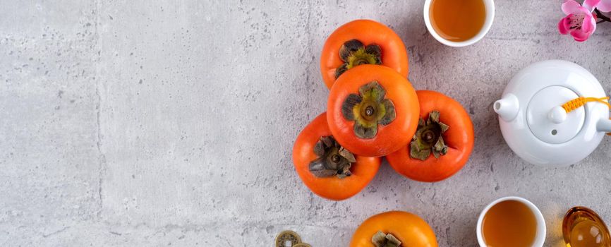 Fresh persimmons on gray table background for Chinese new year fruit design, words on the golden coin means the Dynasty name it made.