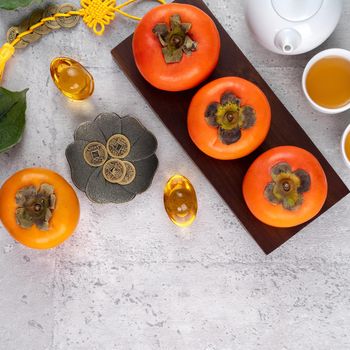 Fresh persimmons on gray table background for Chinese new year fruit design, words on the golden coin means the Dynasty name it made.