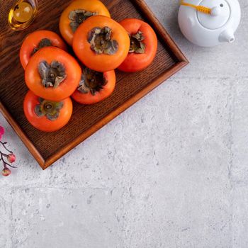 Fresh persimmons on gray table background for Chinese new year fruit design, words on the golden coin means the Dynasty name it made.