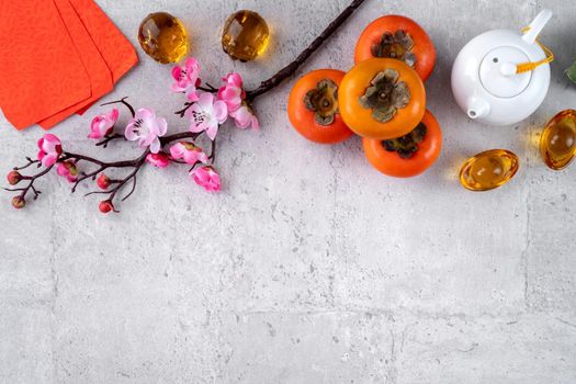 Fresh persimmons on gray table background for Chinese new year fruit design, words on the golden coin means the Dynasty name it made.