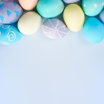 Colorful Easter hunting eggs dyed by colored water with beautiful pattern on pastel blue background, design concept of holiday.