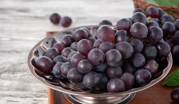 Delicious bunch of grapes fruit on a plate over wooden table background.