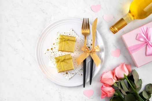 White plate with gift and pink rose flower on marble white table background for Valentine's Day special holiday dating meal concept.