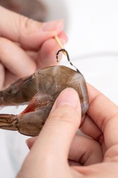 Woman deveins shrimp and pull out intestinal tract line when cooking shrimp.