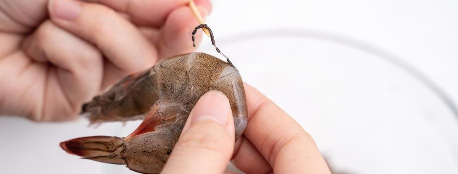 Woman deveins shrimp and pull out intestinal tract line when cooking shrimp.