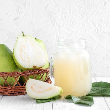 Delicious beautiful guava fruit with fresh juice set isolated on bright white wooden table background, close up.