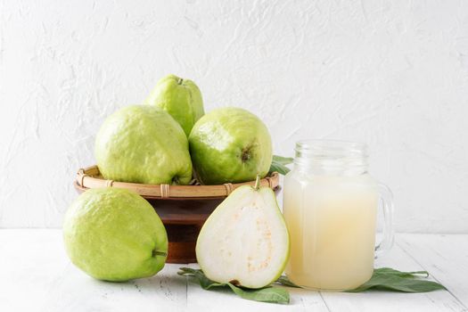 Delicious beautiful guava fruit with fresh juice set isolated on bright white wooden table background, close up.