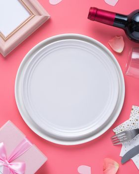 Empty white plate with gift and rose petals for Valentine's Day special holiday dating meal concept.