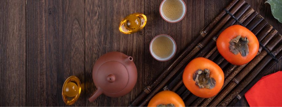 Top view of fresh sweet persimmons kaki with leaves on wooden table background for Chinese lunar new year fruit design concept, the word means blessing is coming.