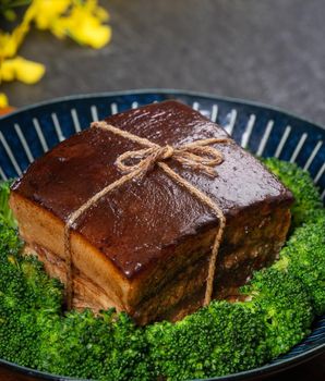 Dong Po Rou (Dongpo pork meat) in a beautiful blue plate with green broccoli vegetable, traditional festive food for Chinese new year cuisine meal, close up.