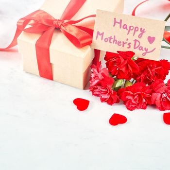 Close up of Mother's Day greeting gift with red flower on modern marble desk, close up, copy space