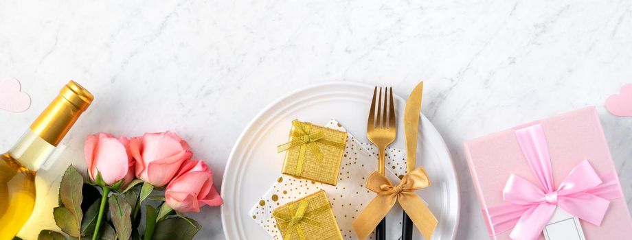 White plate with gift and pink rose flower on marble white table background for Valentine's Day special holiday dating meal concept.